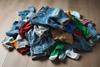 A small pile of crumpled, untidy children's clothes, mainly trousers, all colours