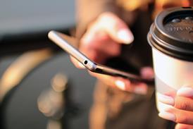 Close-up of a person holding a smartphone and a disposable coffee mug