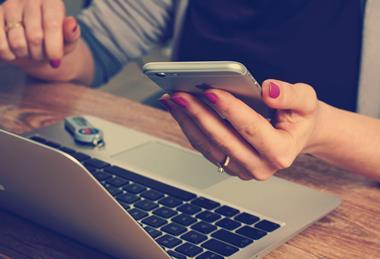 Person using a smartphone and laptop